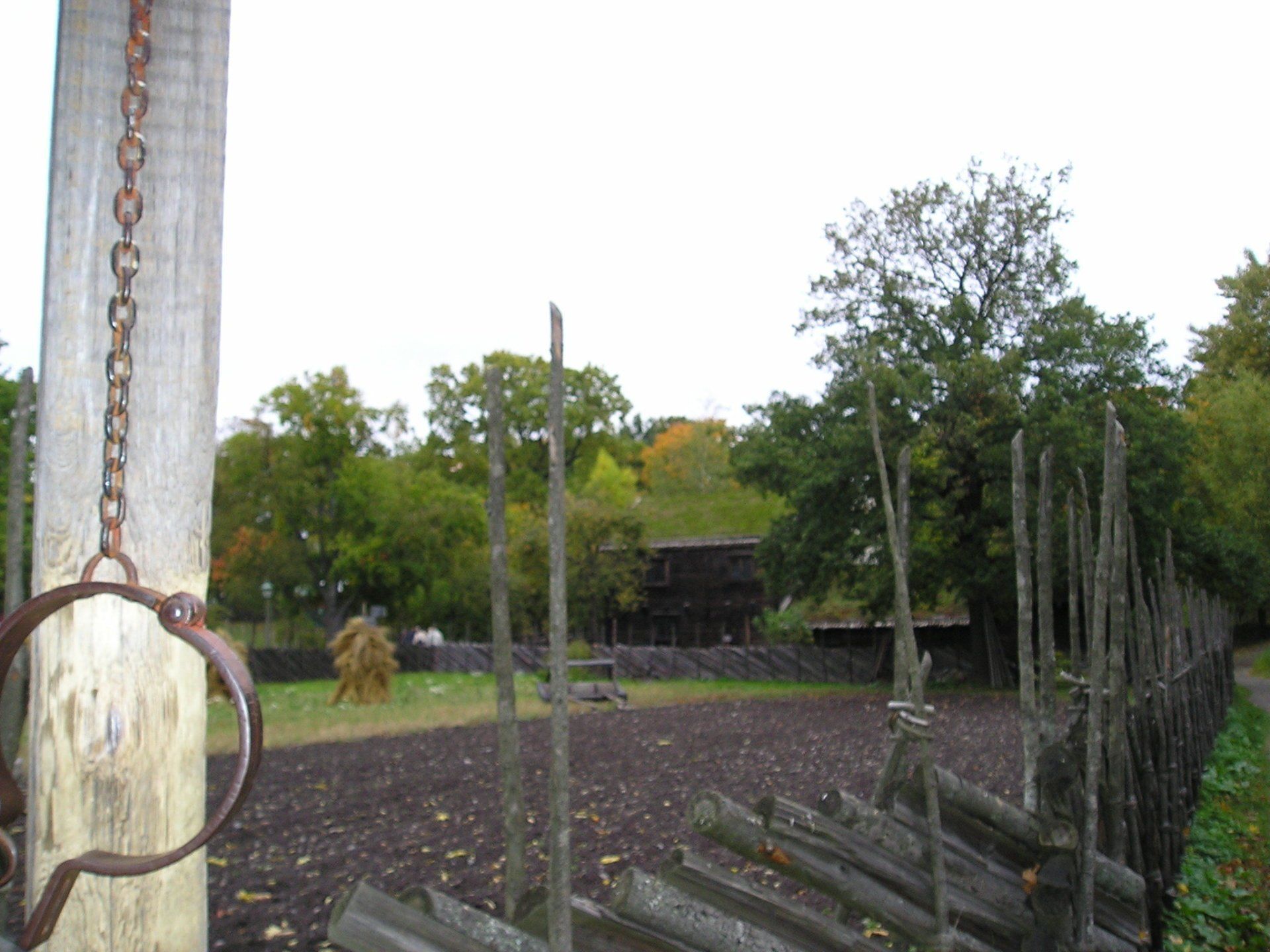 A chain is hanging from a wooden post in a field