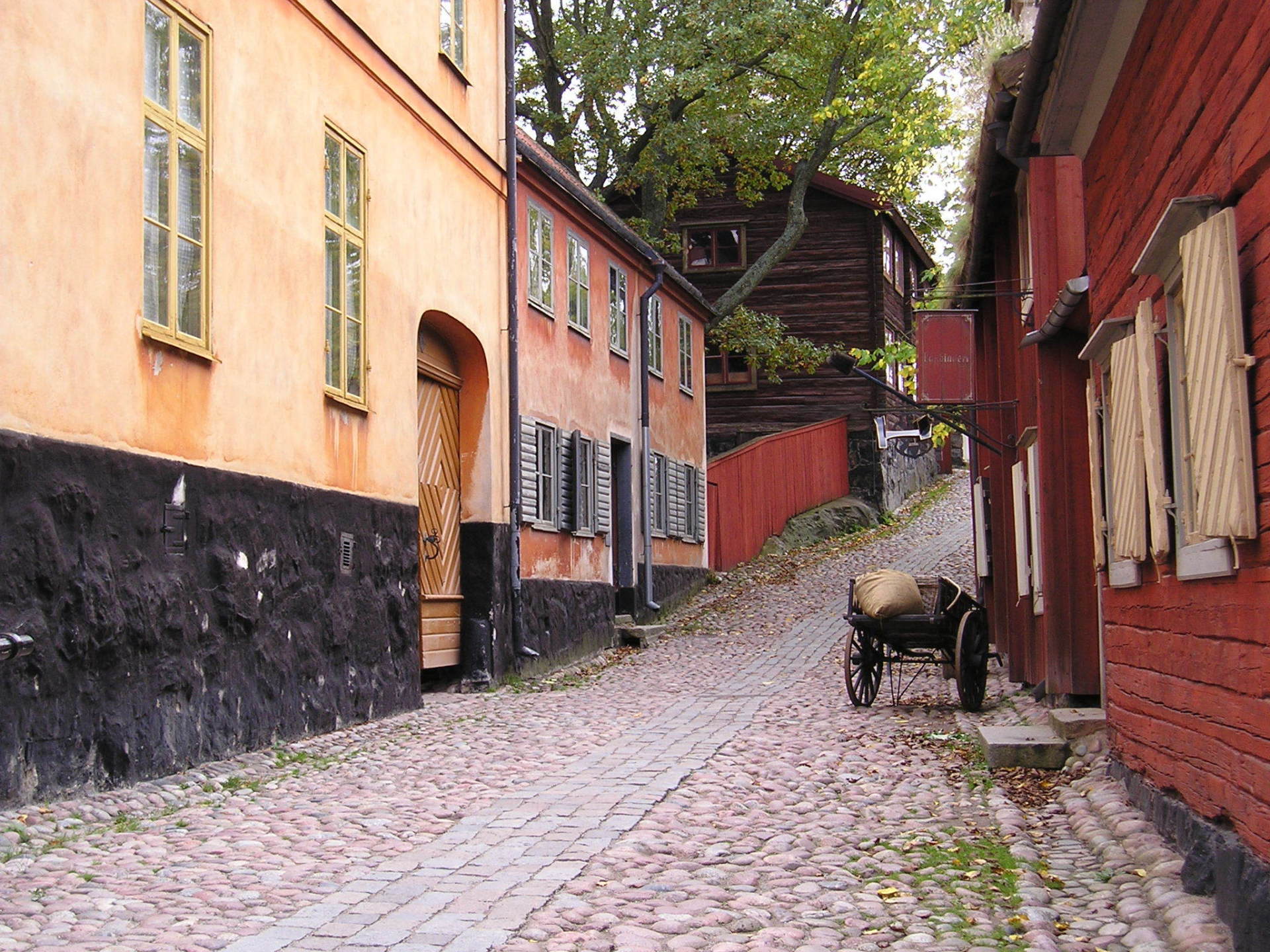 A horse drawn carriage is parked on the side of a cobblestone street
