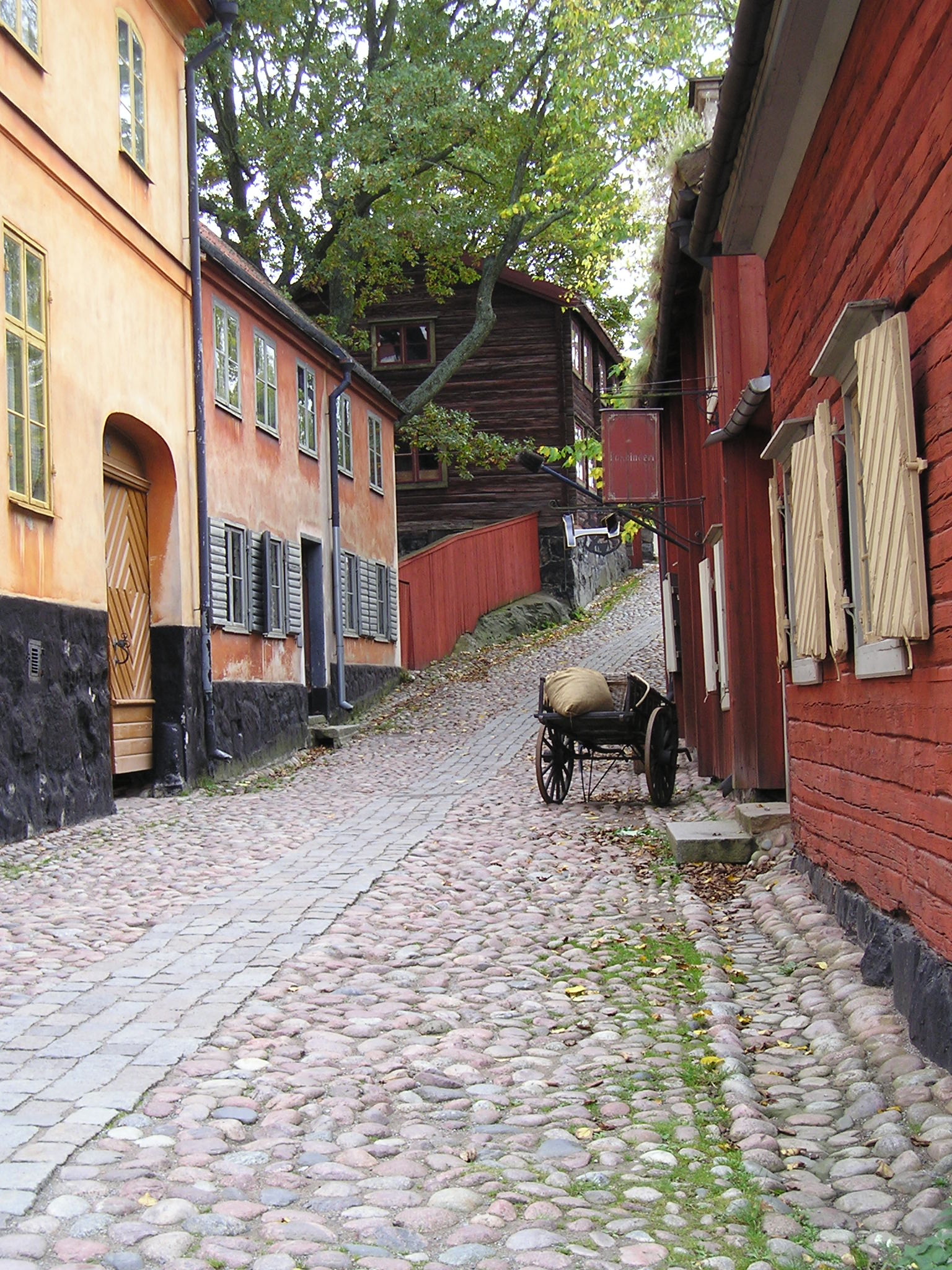 A horse drawn carriage is parked on the side of a cobblestone street