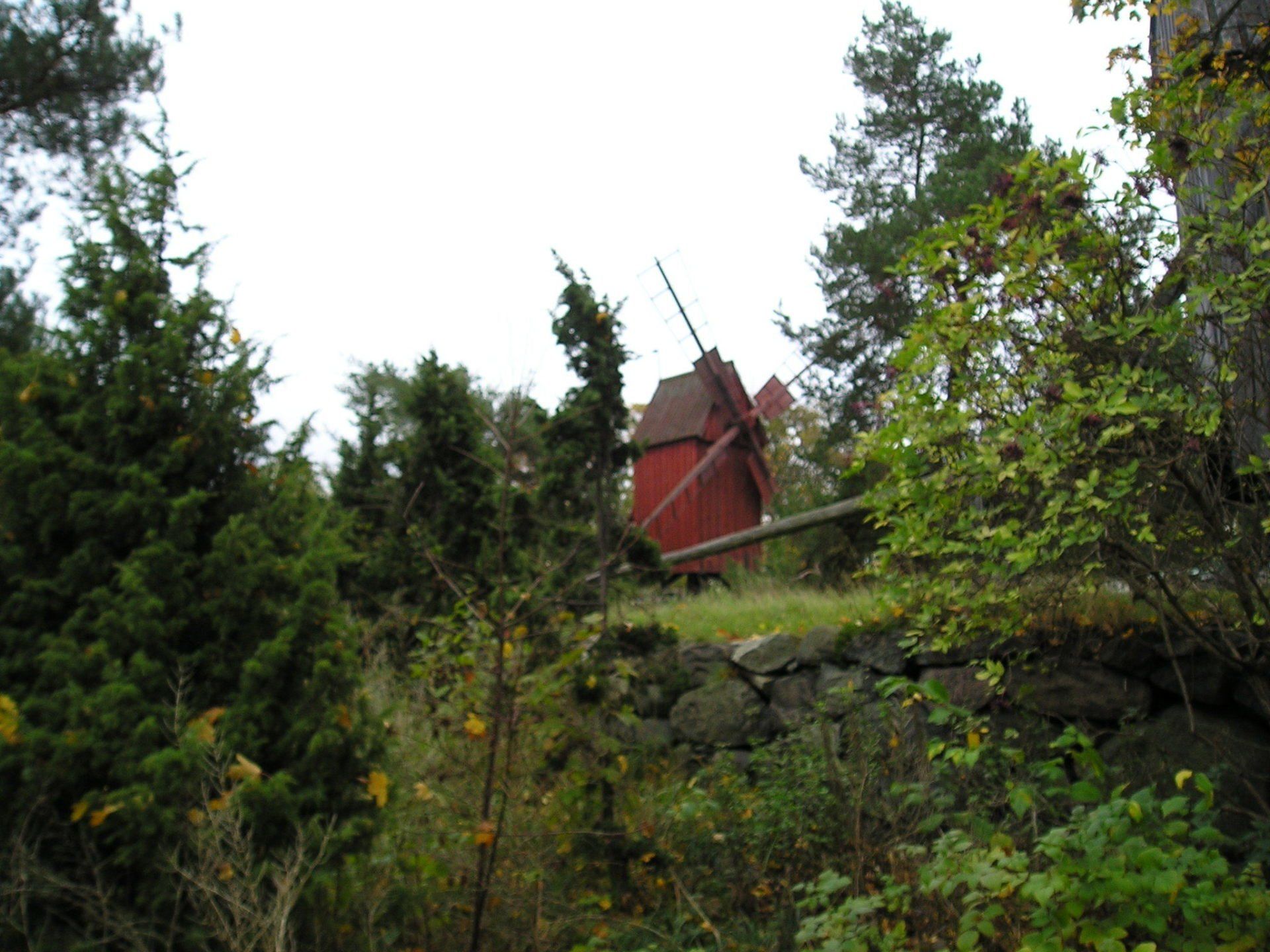 A red windmill is in the middle of a forest