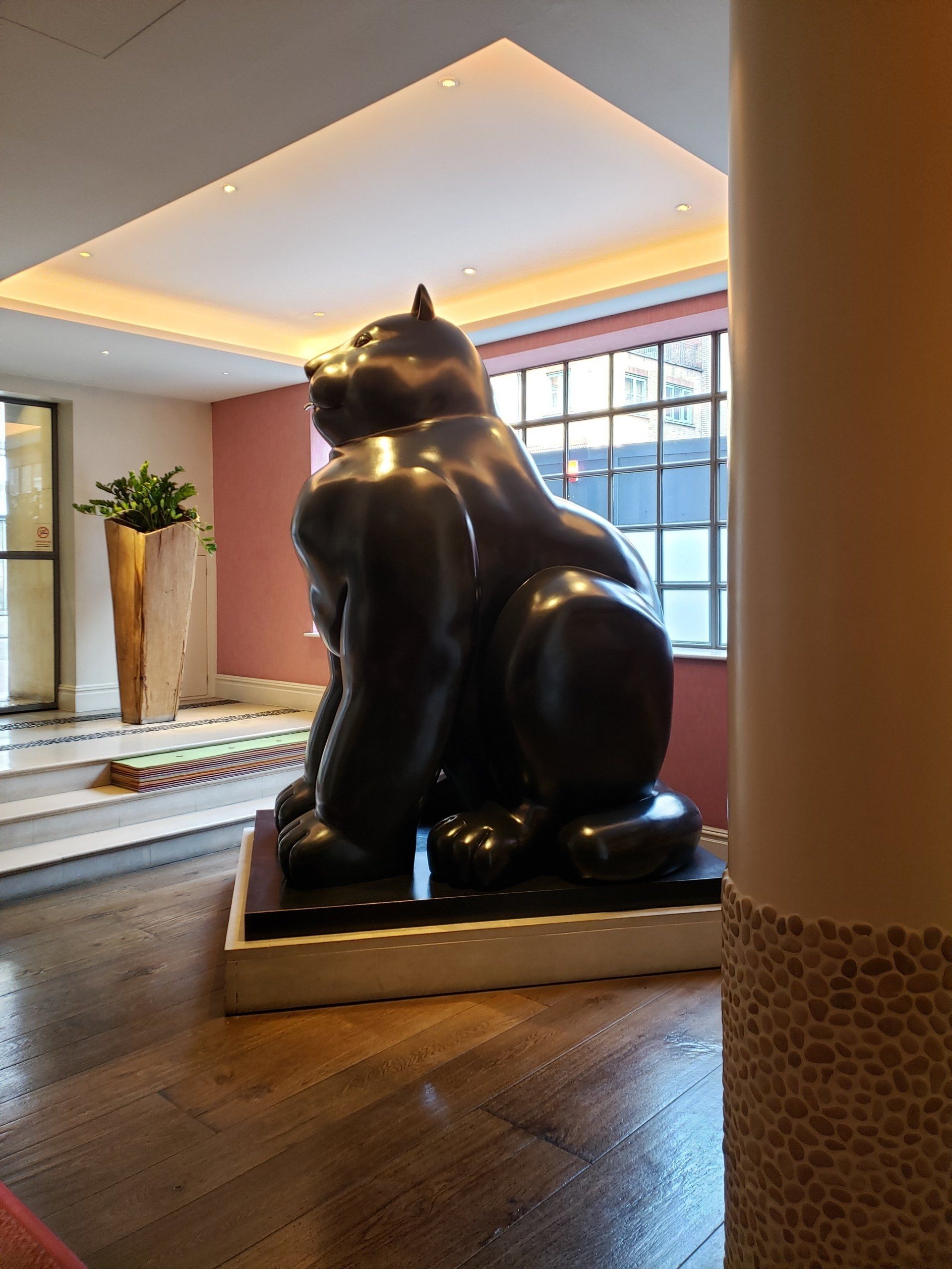 A statue of a gorilla is sitting on a wooden floor in a room.