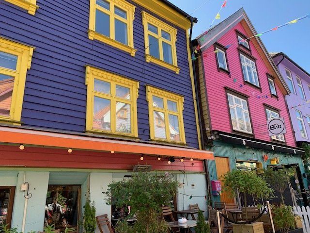 A purple building with yellow windows next to a pink building with yellow windows.