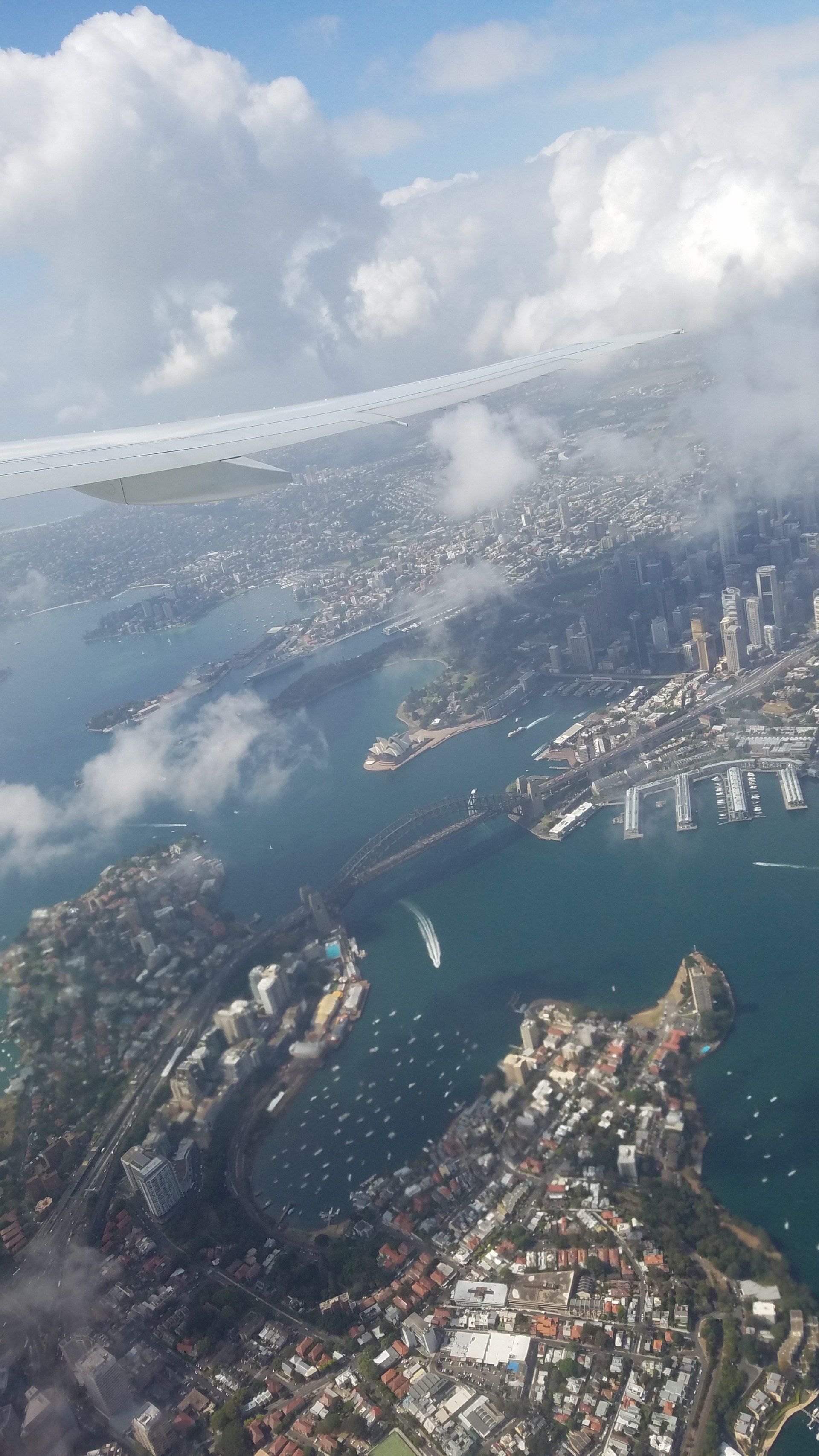 An aerial view of a city and a body of water from an airplane window.