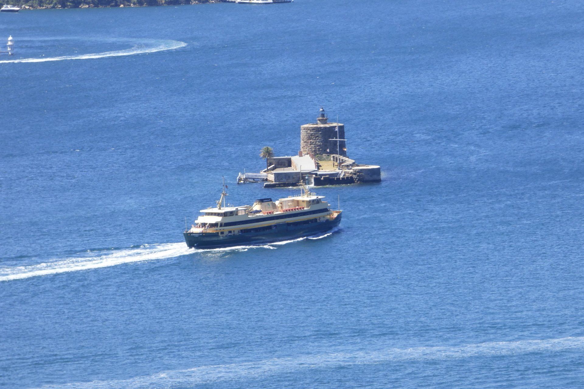 Two boats are floating in the ocean near a small island