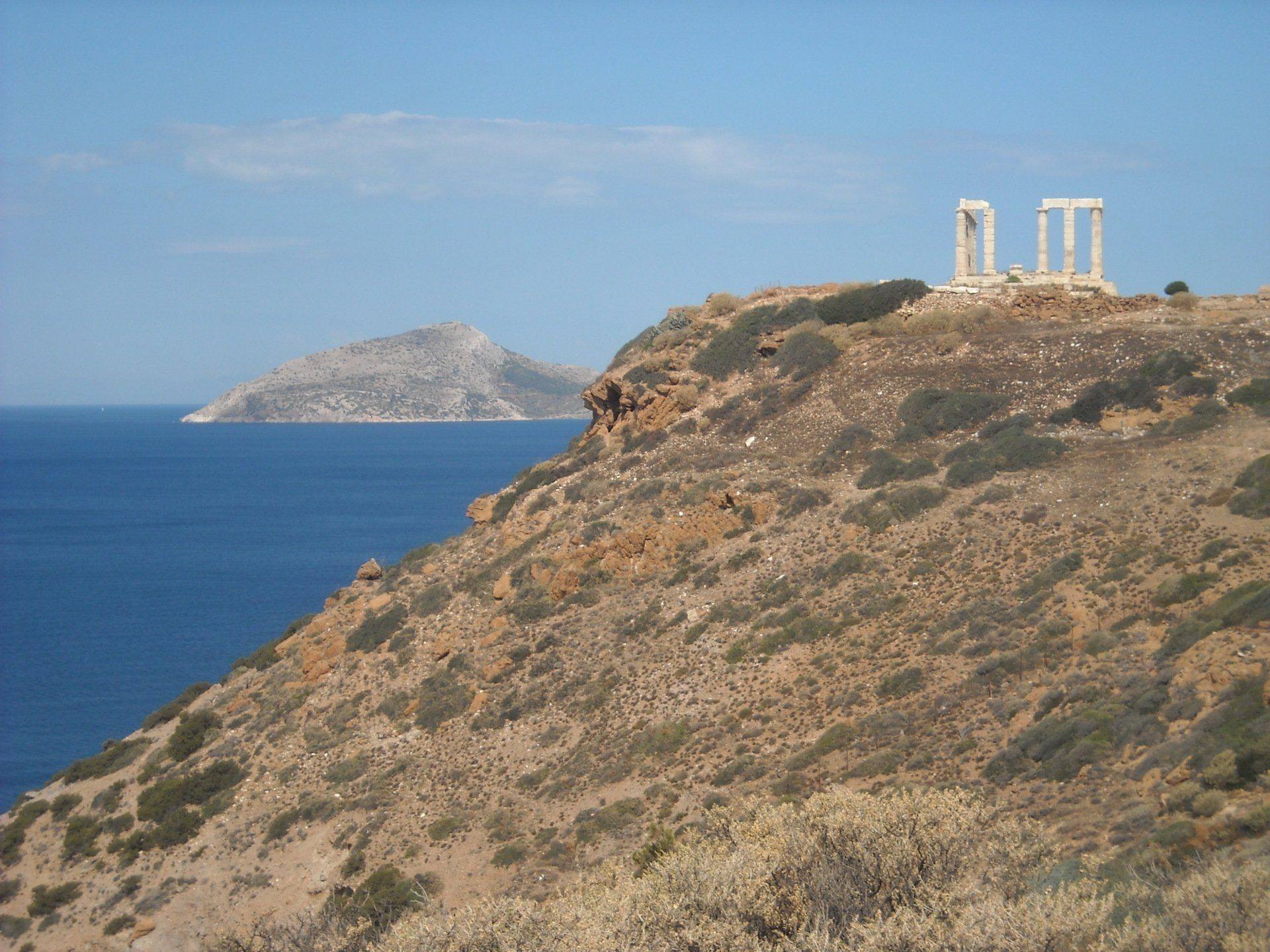 A cliff overlooking the ocean with a small island in the distance
