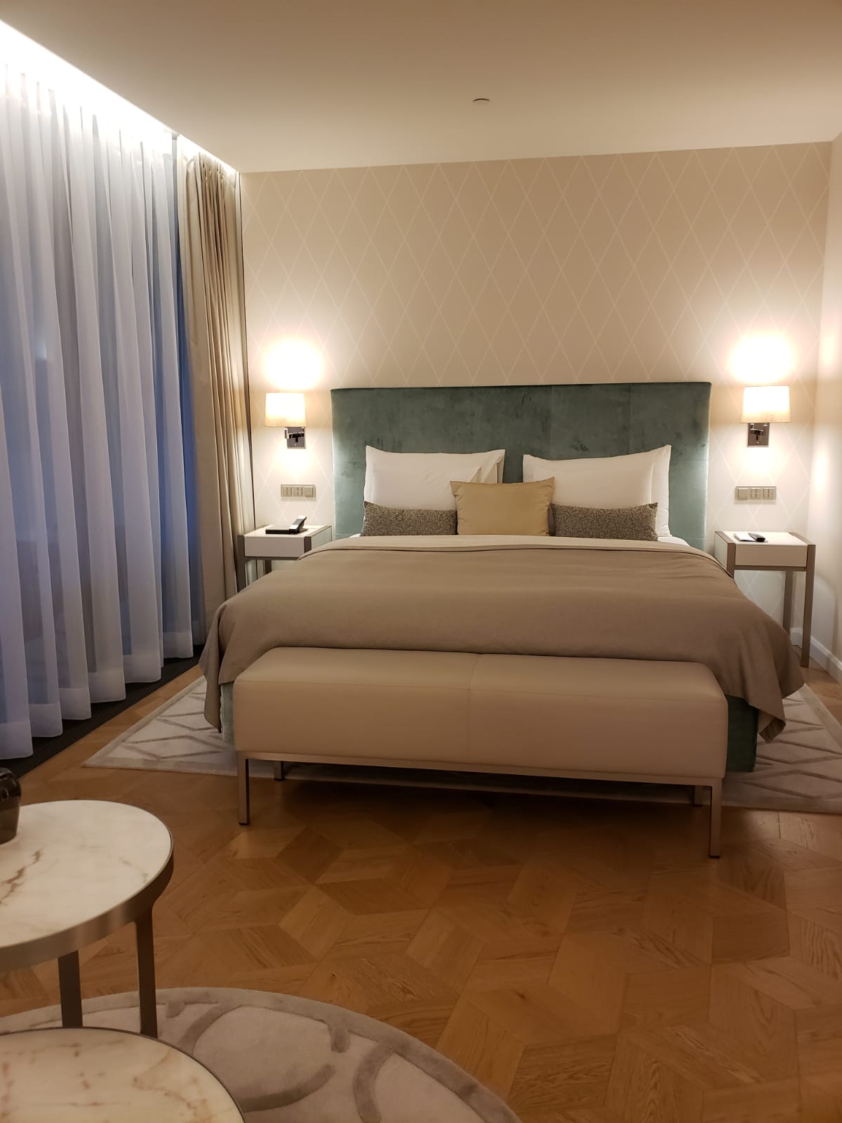 A hotel room with a large bed and a bench