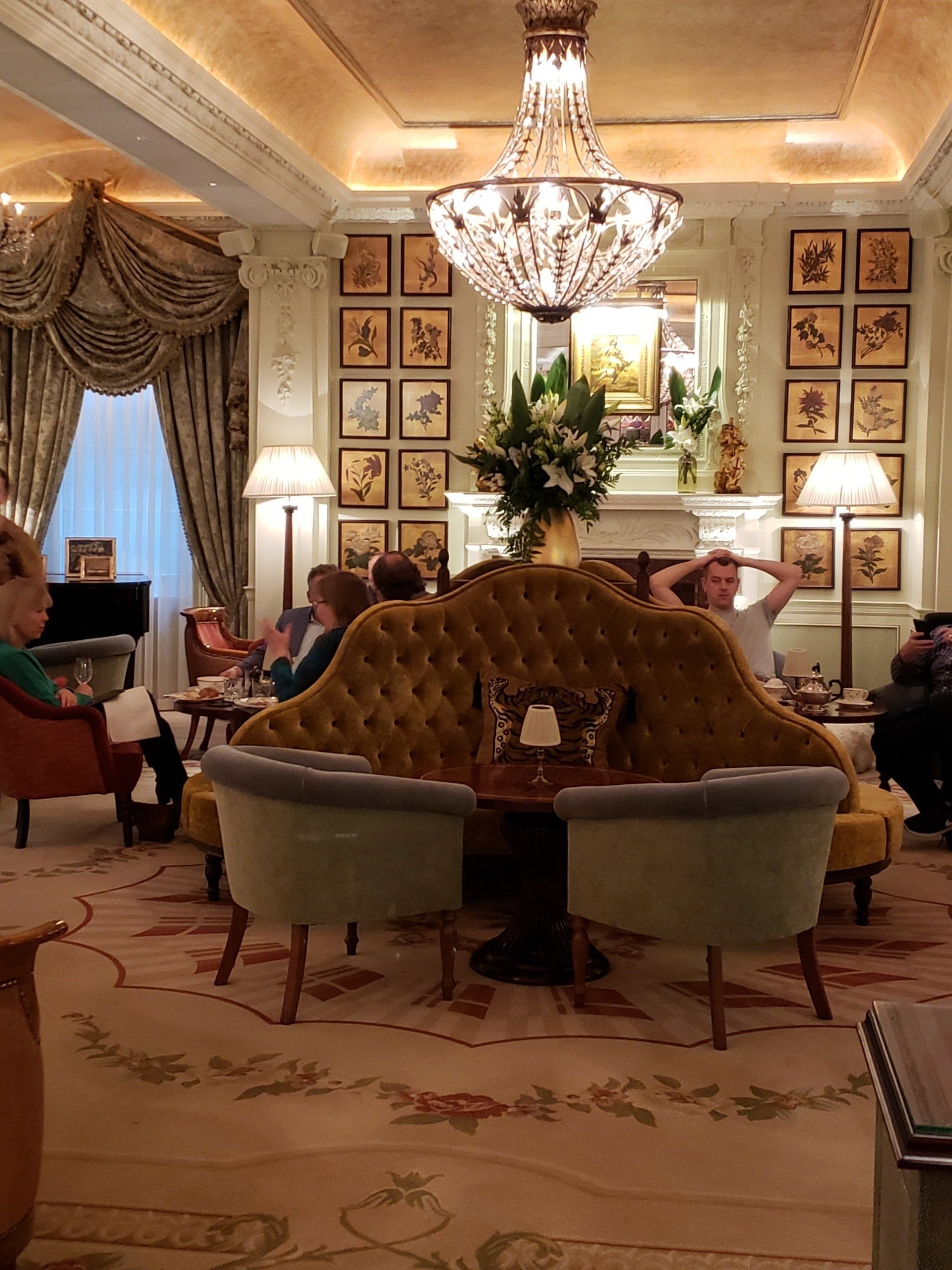 A group of people are sitting in a living room with a chandelier hanging from the ceiling.