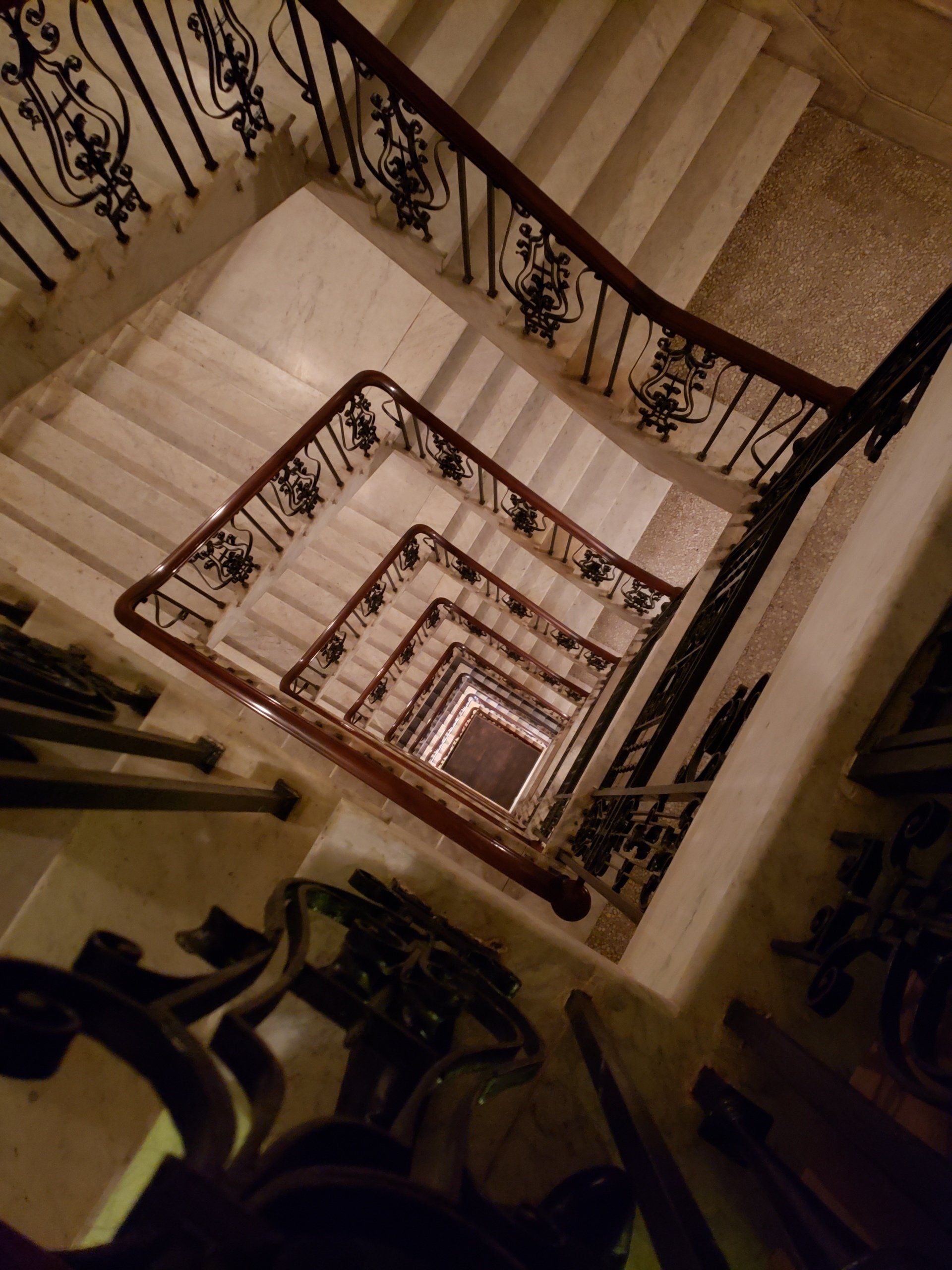 Looking down a spiral staircase with a wrought iron railing