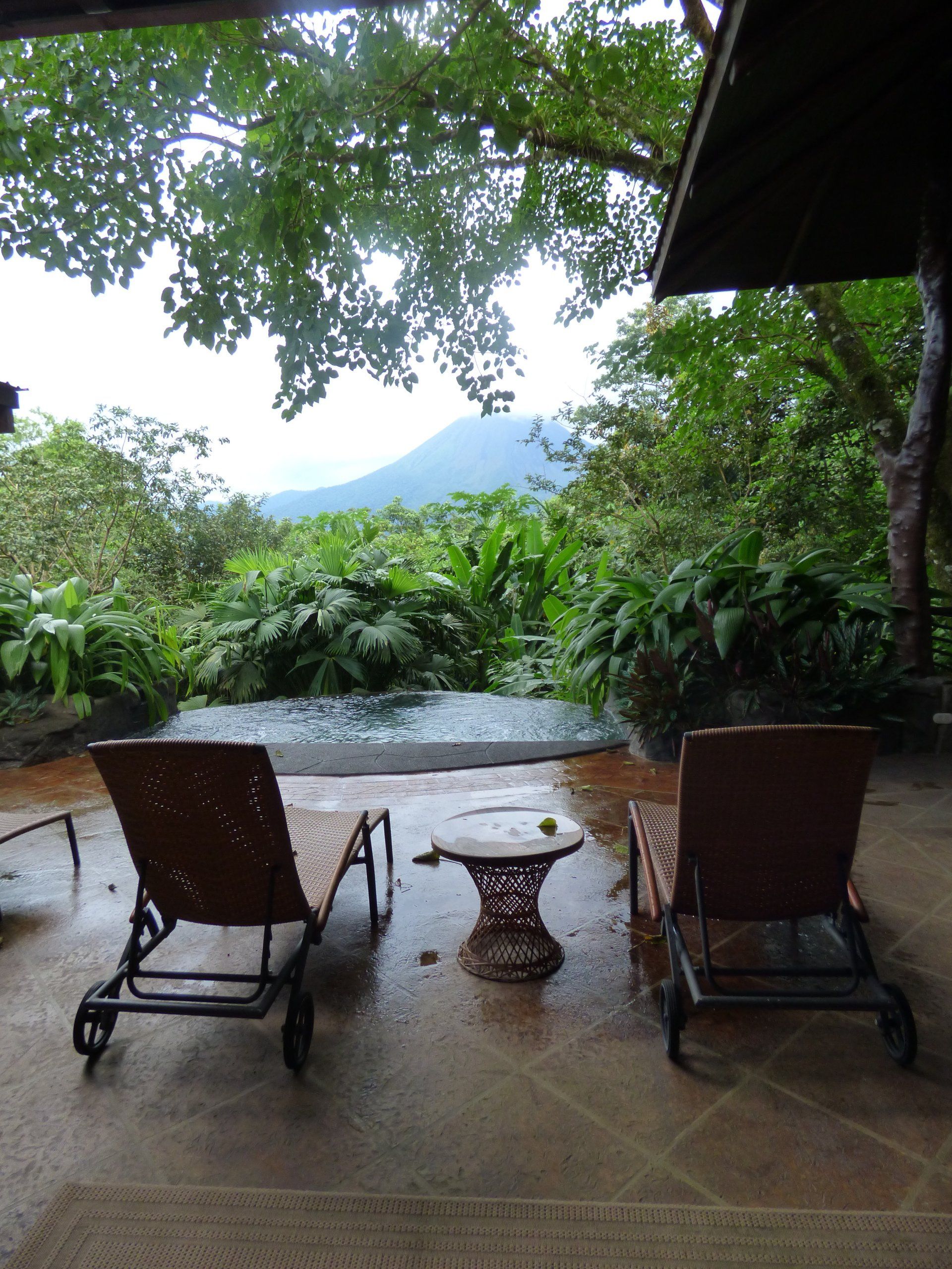 Two chairs and a table on a patio with a mountain in the background