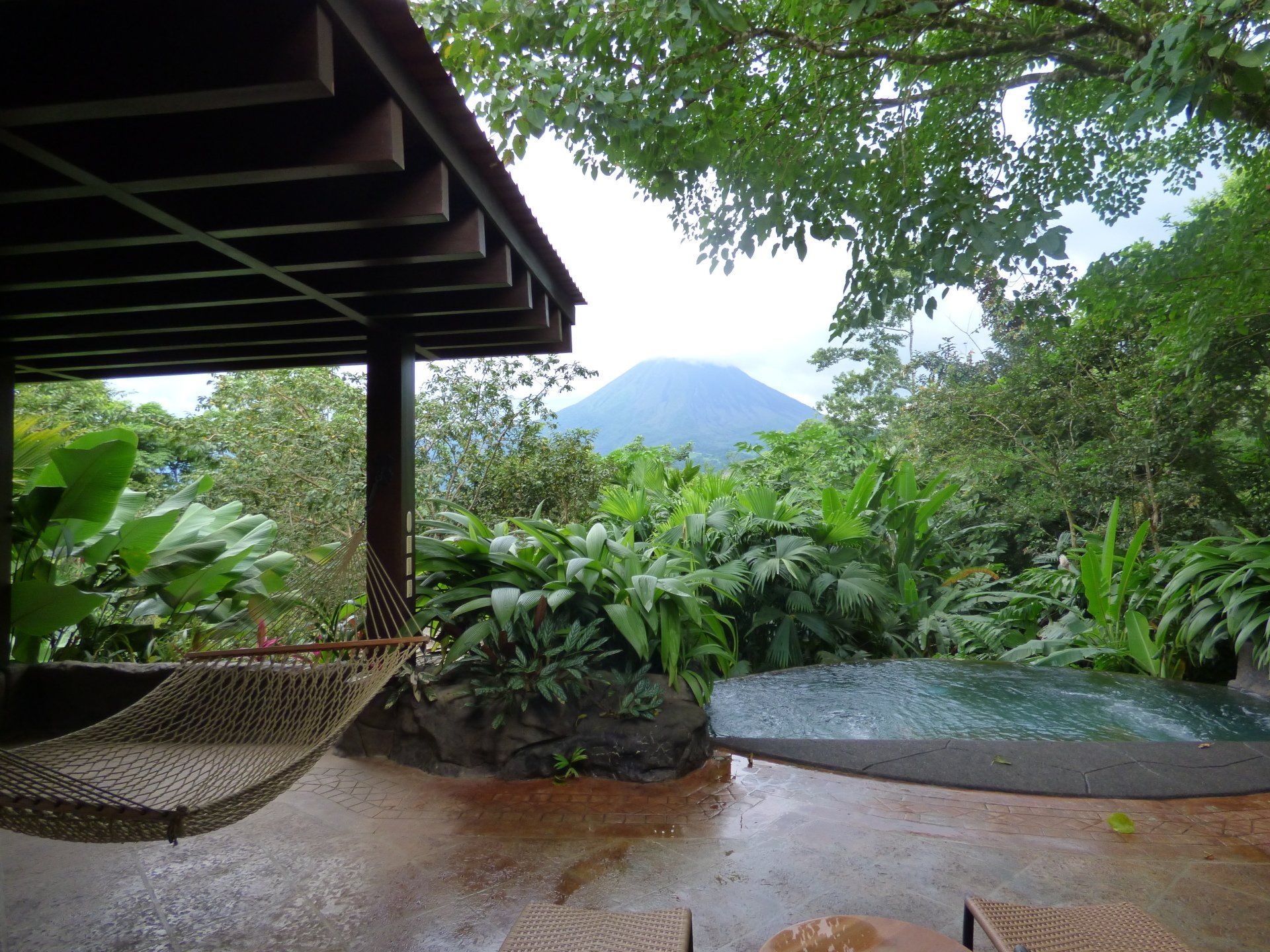 A hammock is hanging over a pool with a mountain in the background