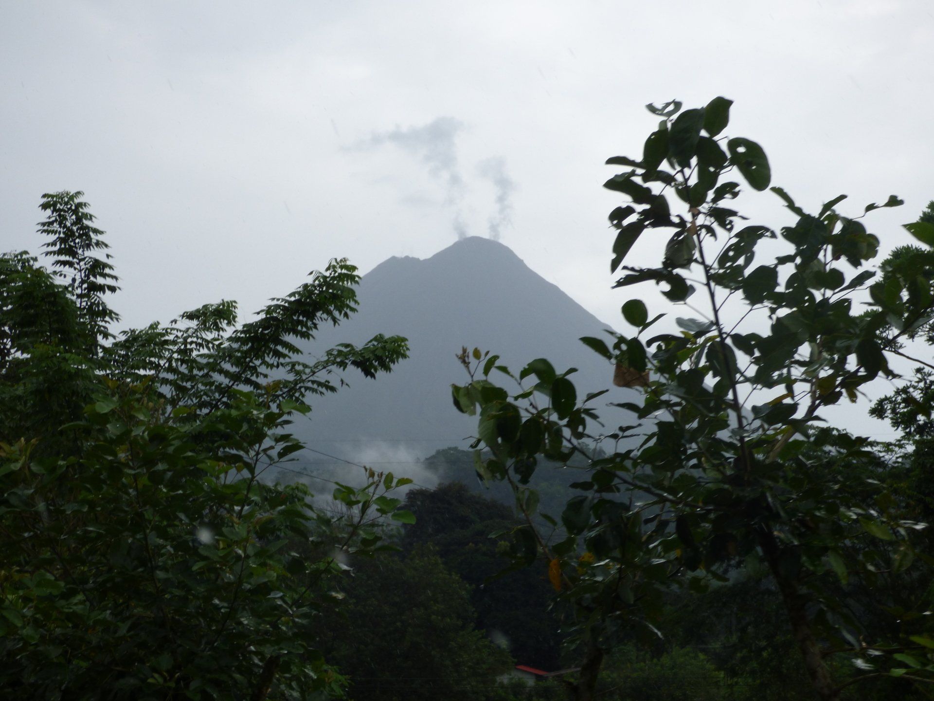 A mountain with smoke coming out of it surrounded by trees