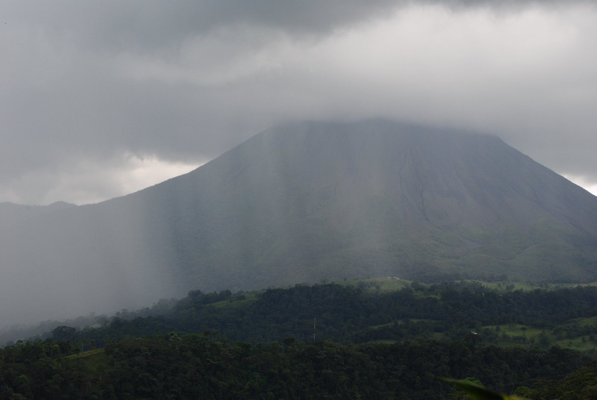 The sun is shining through the clouds on a mountain.
