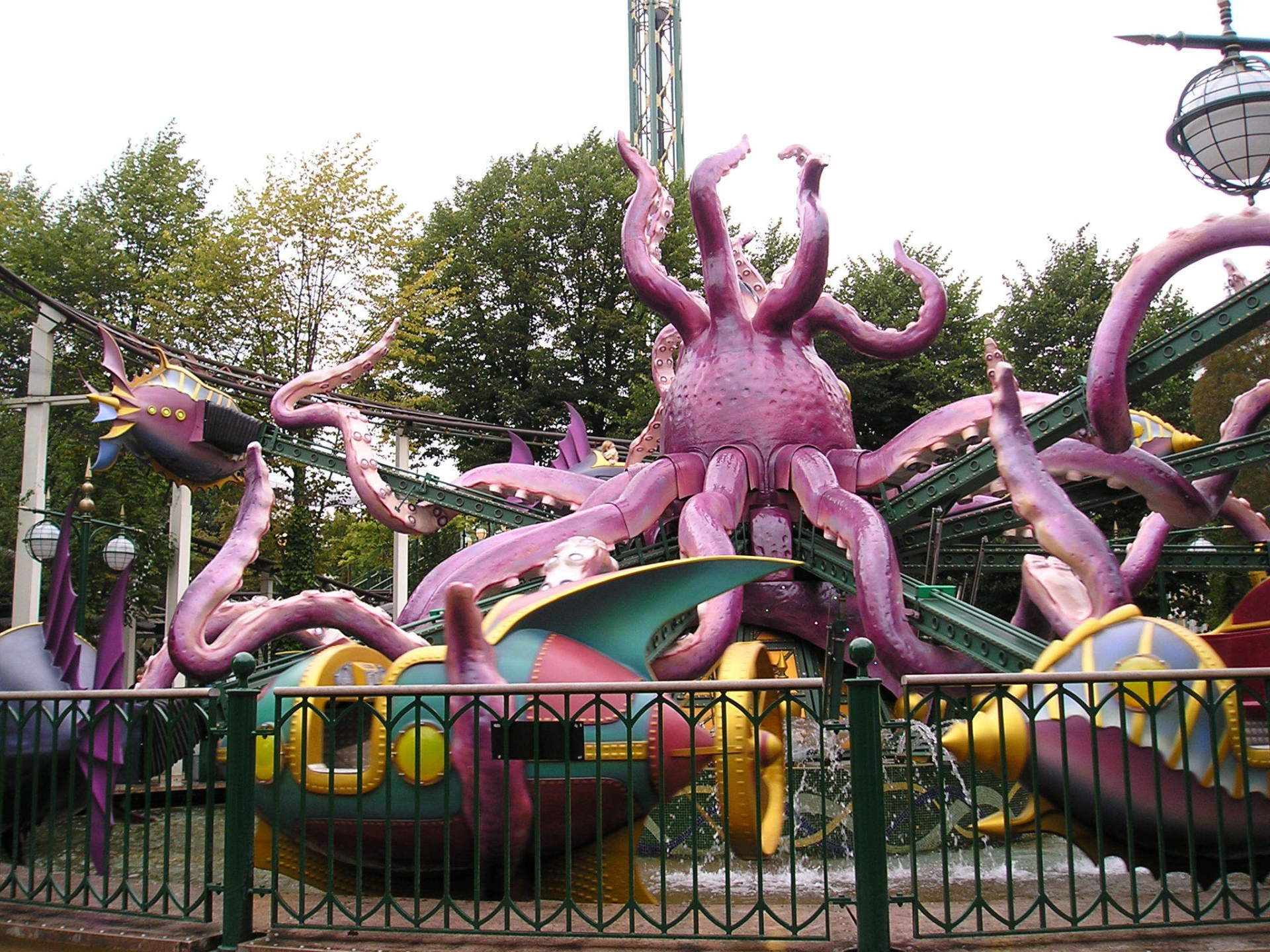 A purple octopus is behind a fence at an amusement park