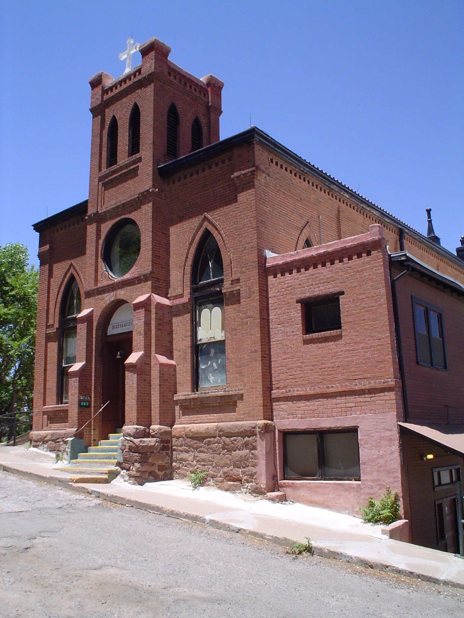 A large red brick building with a steeple and a cross on top