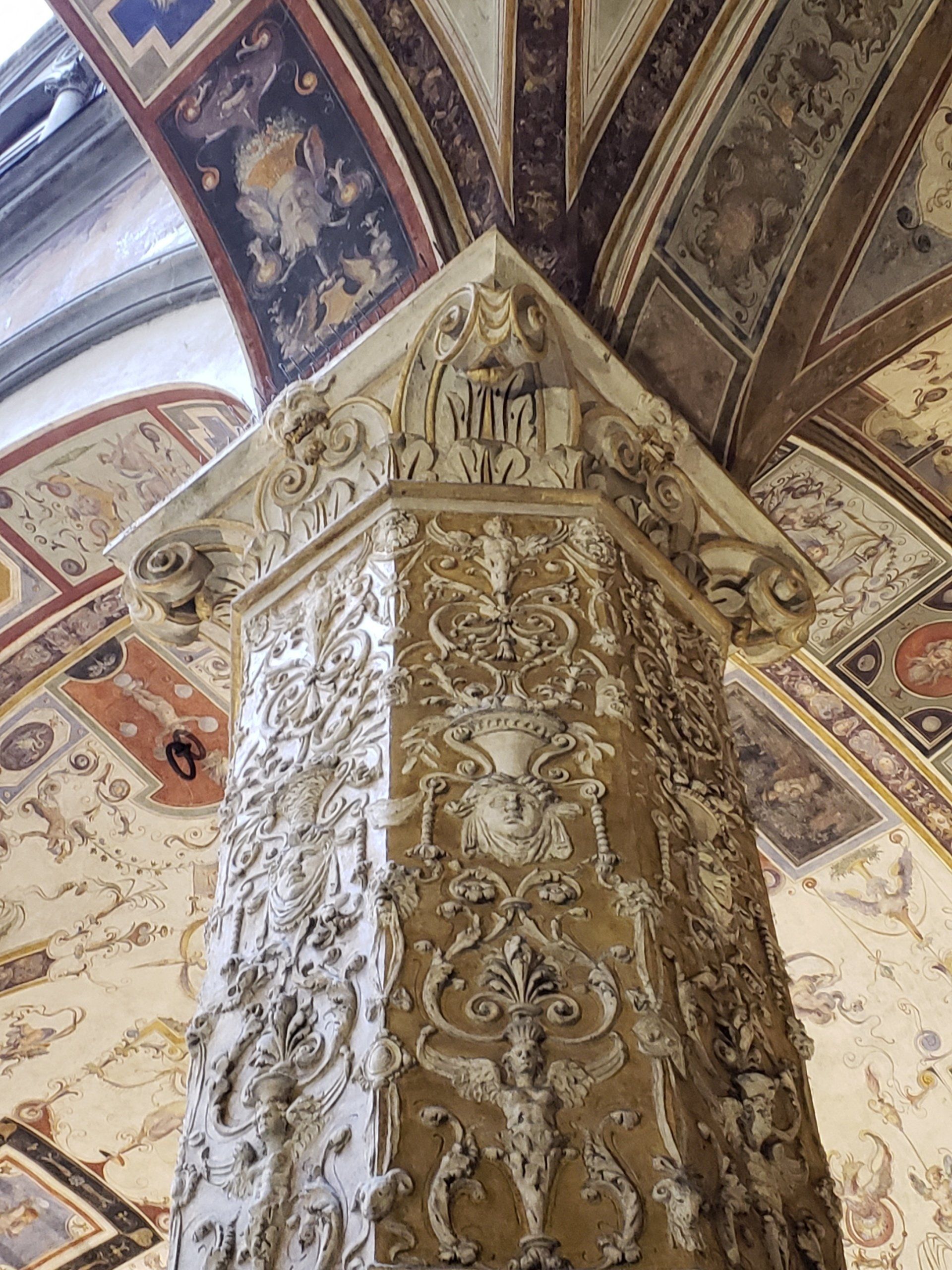 A very ornate column in a building with a very ornate ceiling.