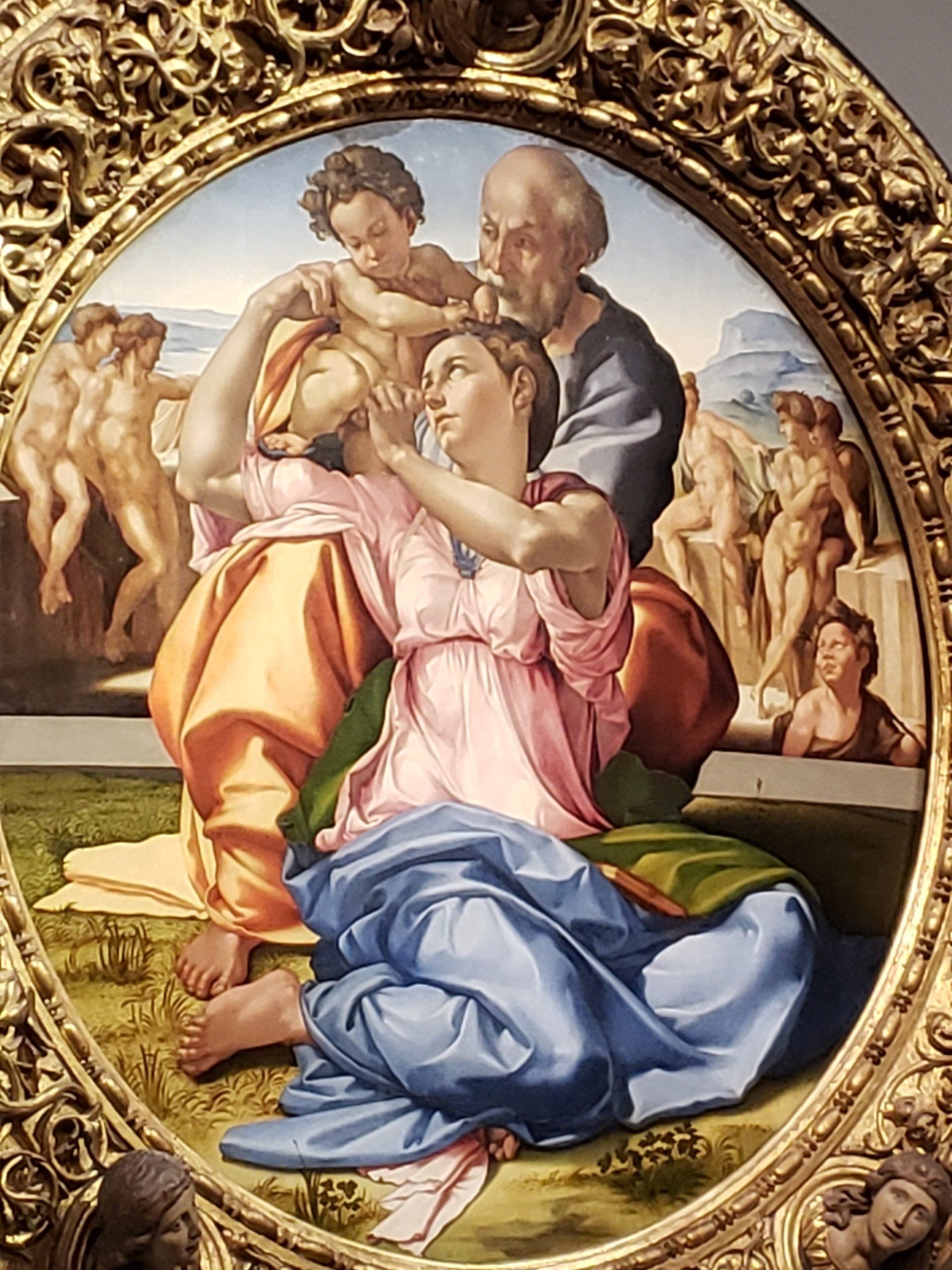 A painting of a man and woman holding a baby in a gold frame.