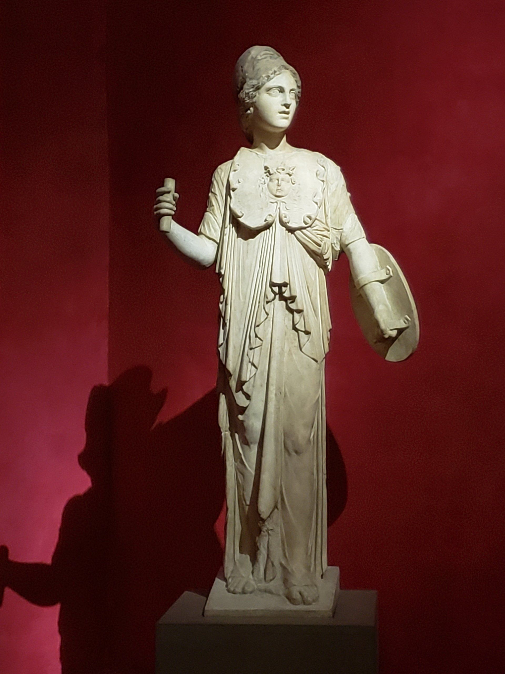 A statue of a woman standing in front of a red wall
