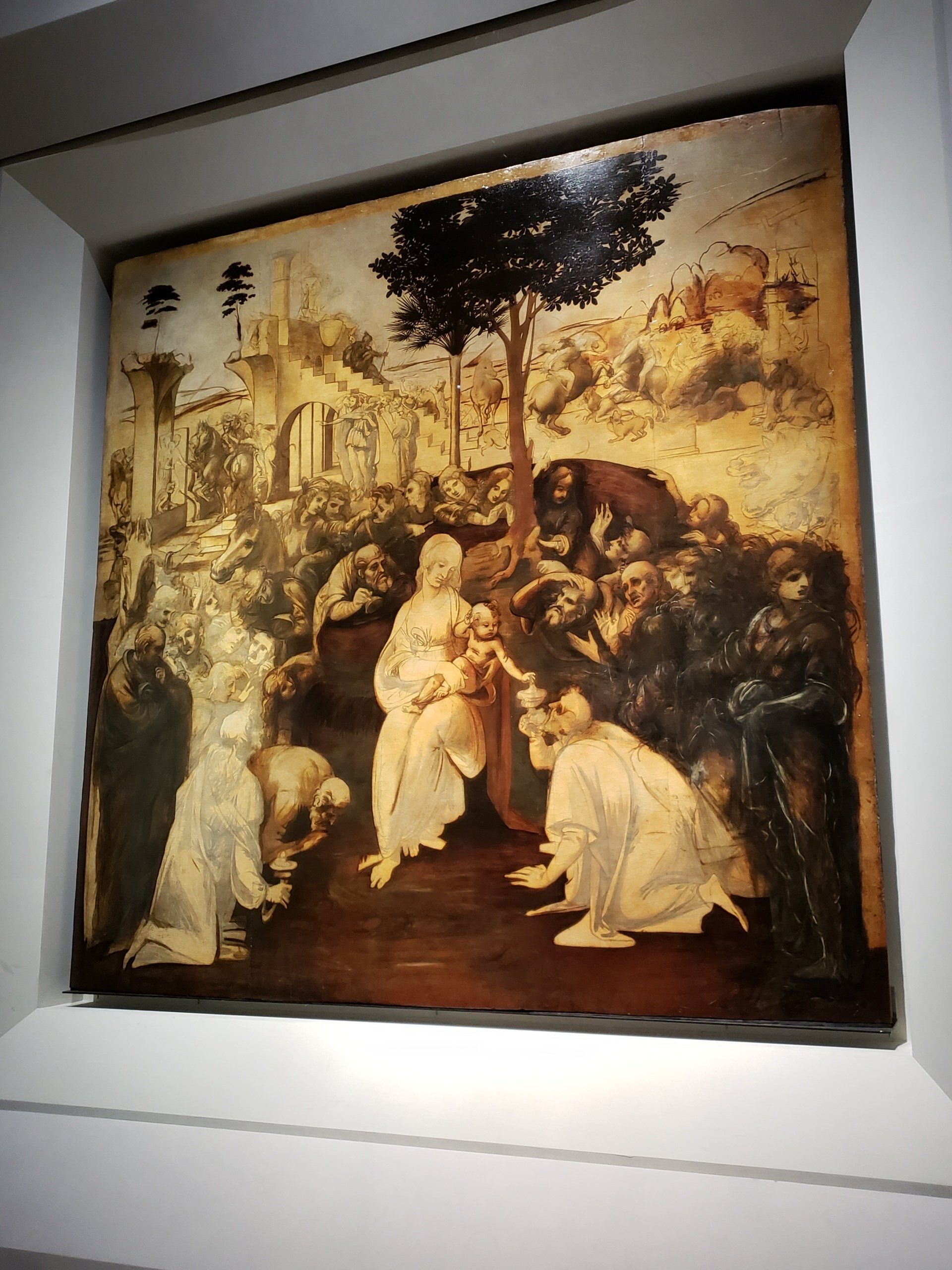 A painting of jesus surrounded by people is hanging on a wall