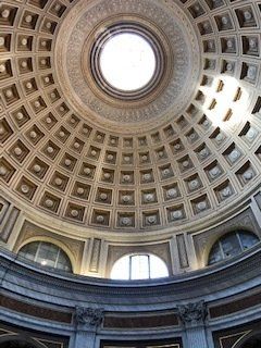 Looking up at the dome of a building with a window in the middle.