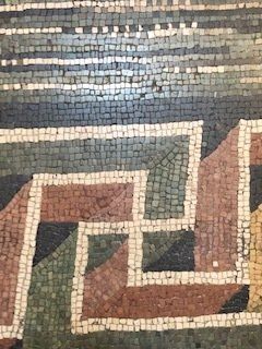 A close up of a mosaic floor with a maze pattern.