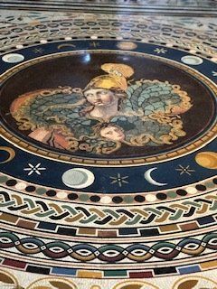 There is a painting of a woman in a helmet on the floor.