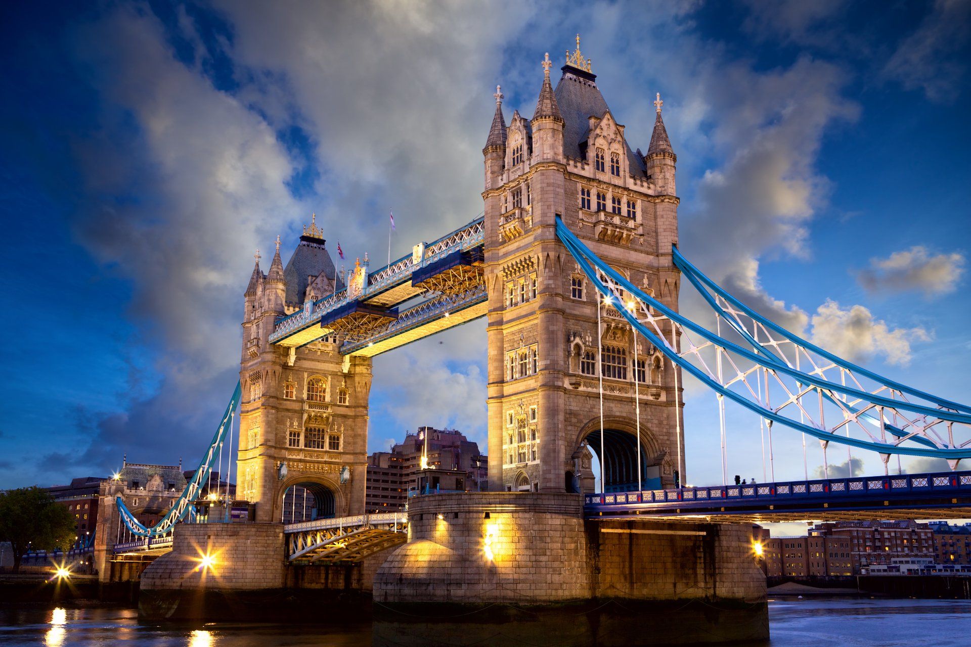 The tower bridge in london is lit up at night.