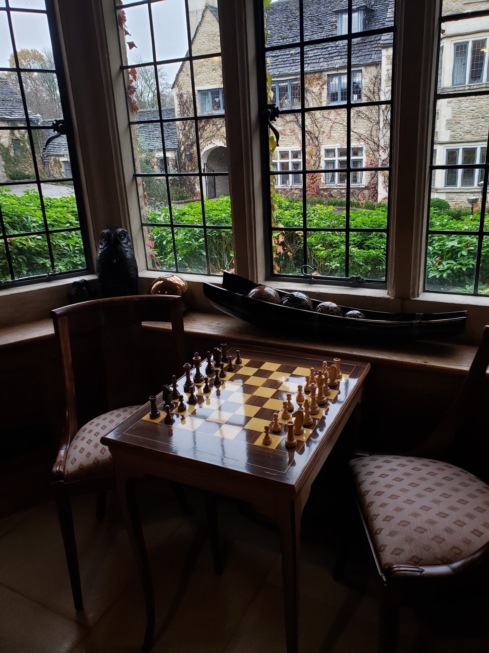A chess board is on a table in front of a window.