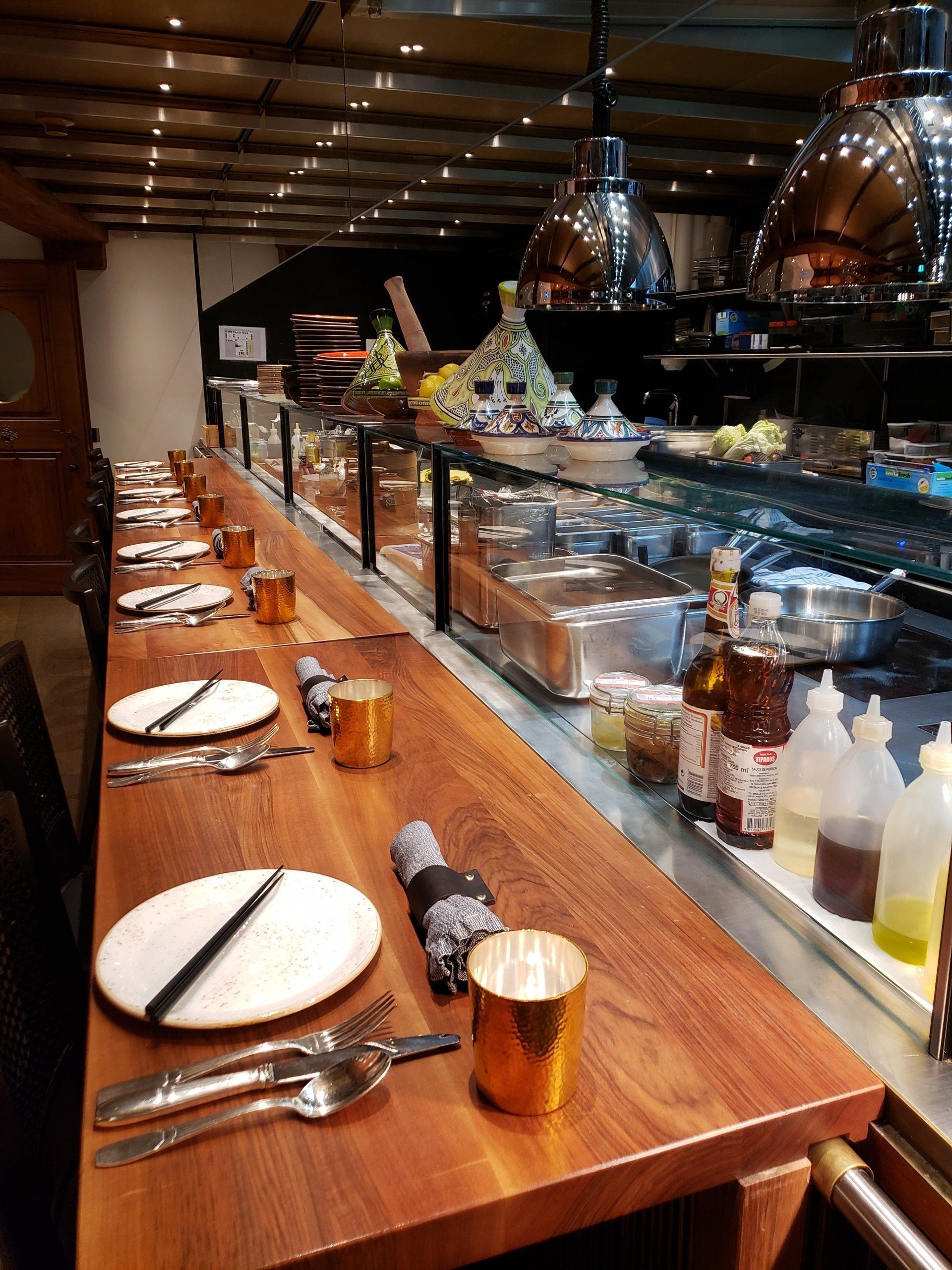 A long wooden table with plates and silverware on it in a restaurant.