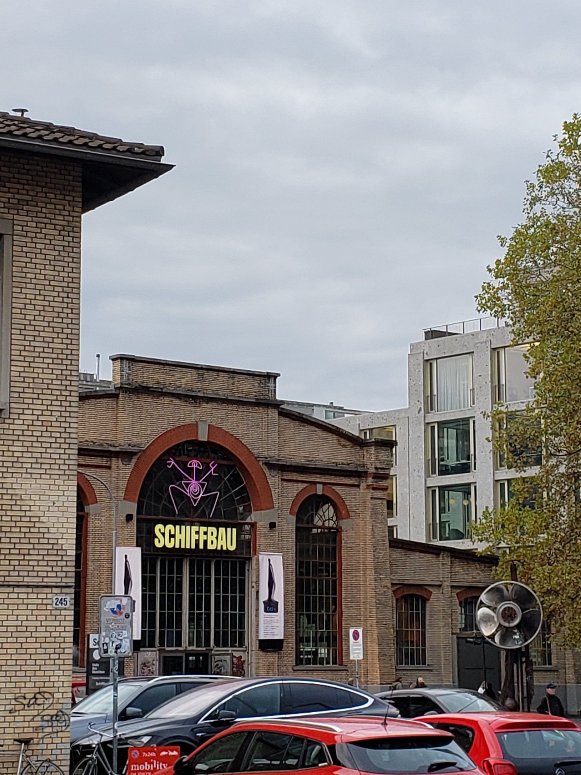 A group of cars are parked in front of a building with a sign that says schiffbau.