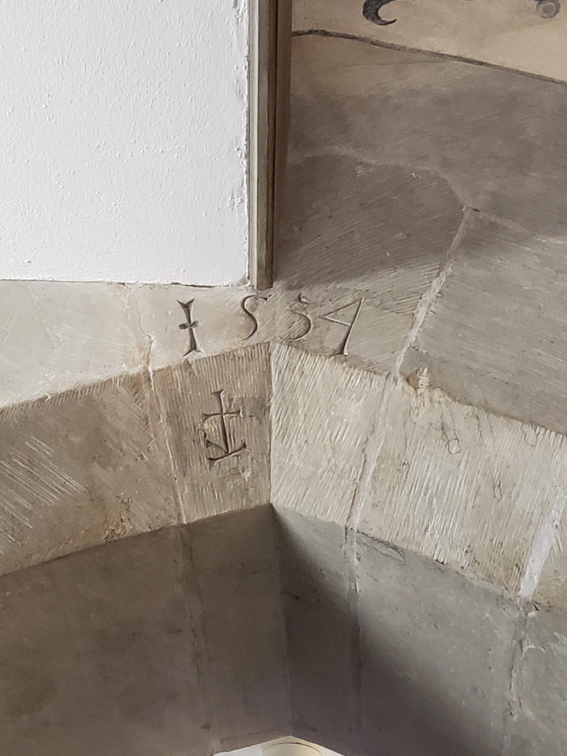 A close up of a stone wall with a cross carved into it.