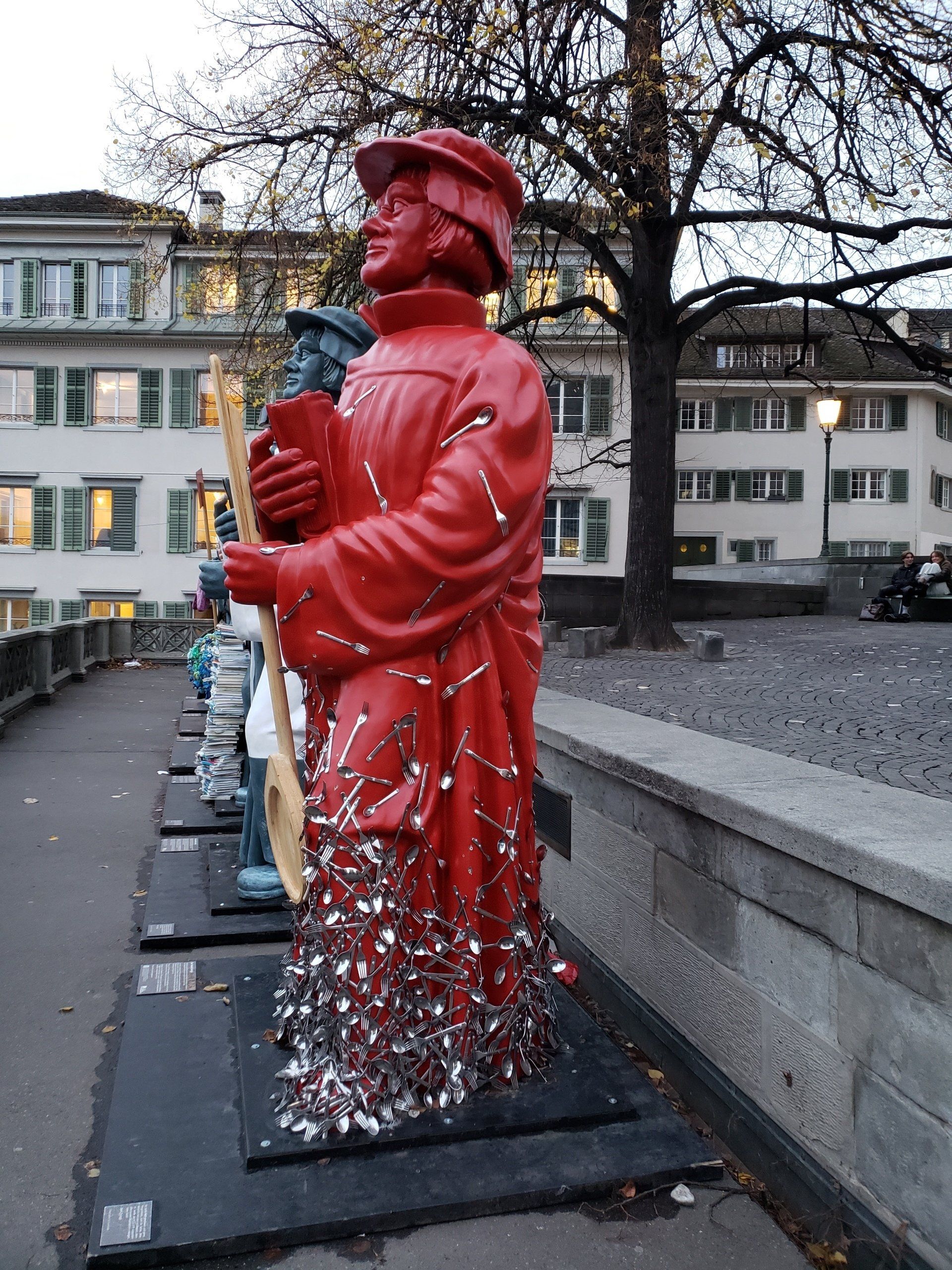 A row of red statues are lined up on a sidewalk
