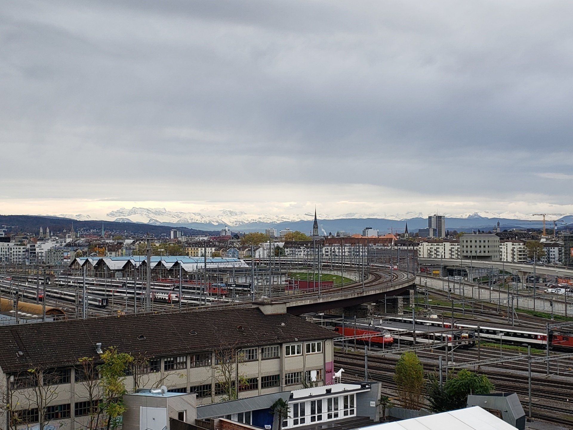 An aerial view of a train yard in a city on a cloudy day.