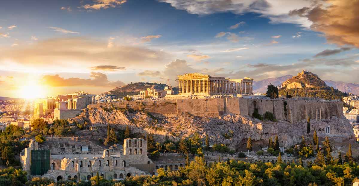 The sun is setting over the acropolis in athens , greece.