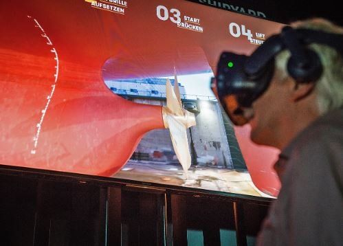 A man wearing a virtual reality headset is looking at a boat on a screen.