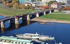 An aerial view of a bridge over a river with boats docked in the water.