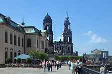 A group of people are walking across a bridge in front of a large building.