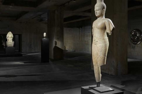 A statue of a woman standing on a pedestal in a dark room.