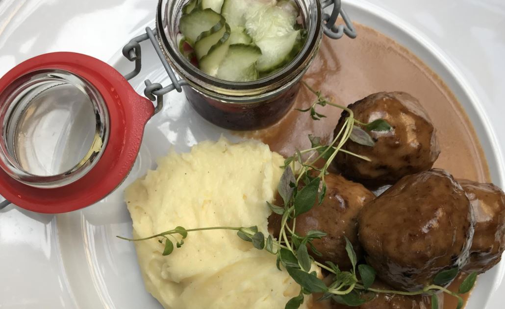 A white plate topped with meatballs , mashed potatoes and sauce.