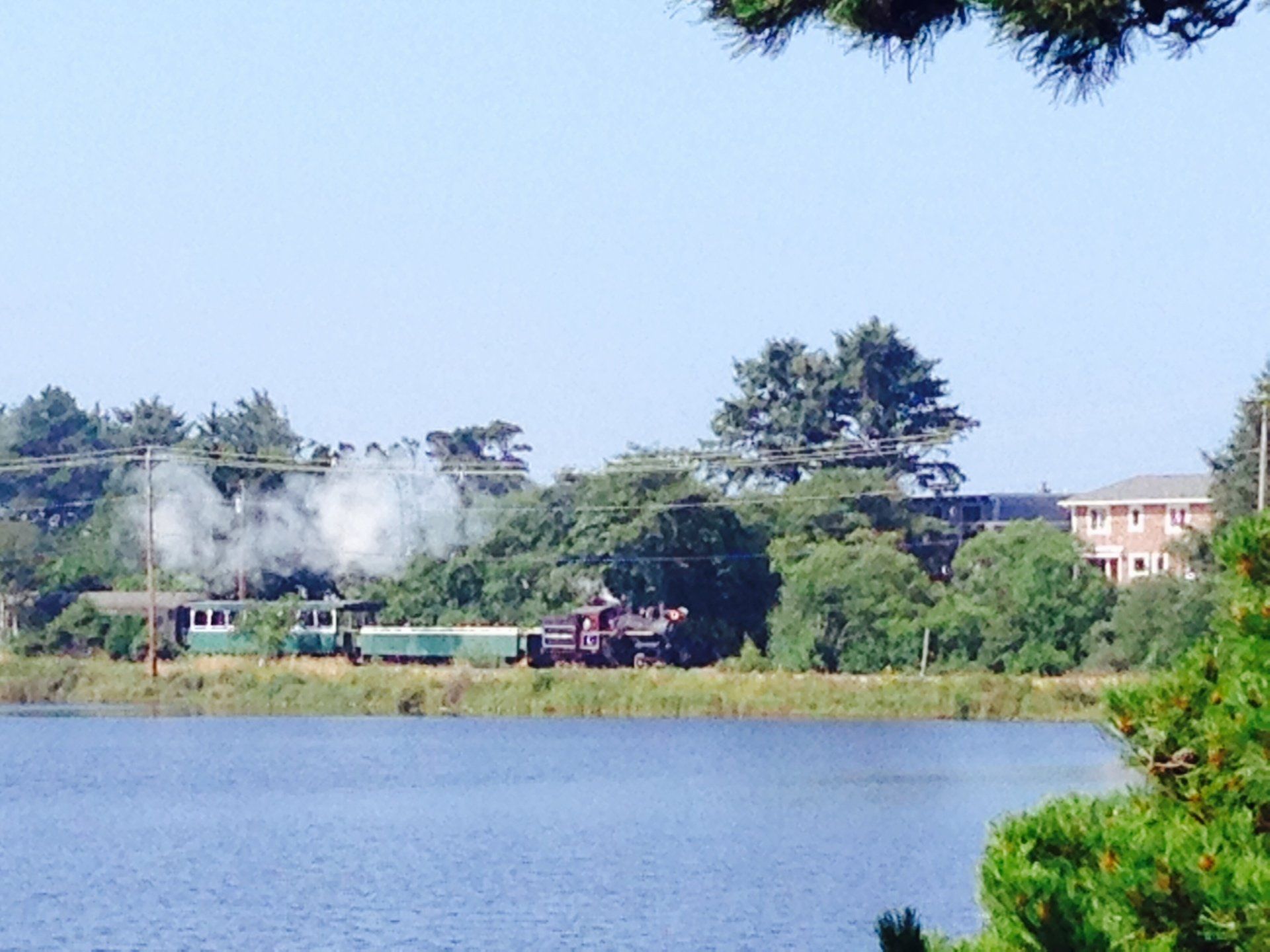 A train is going down the tracks next to a body of water