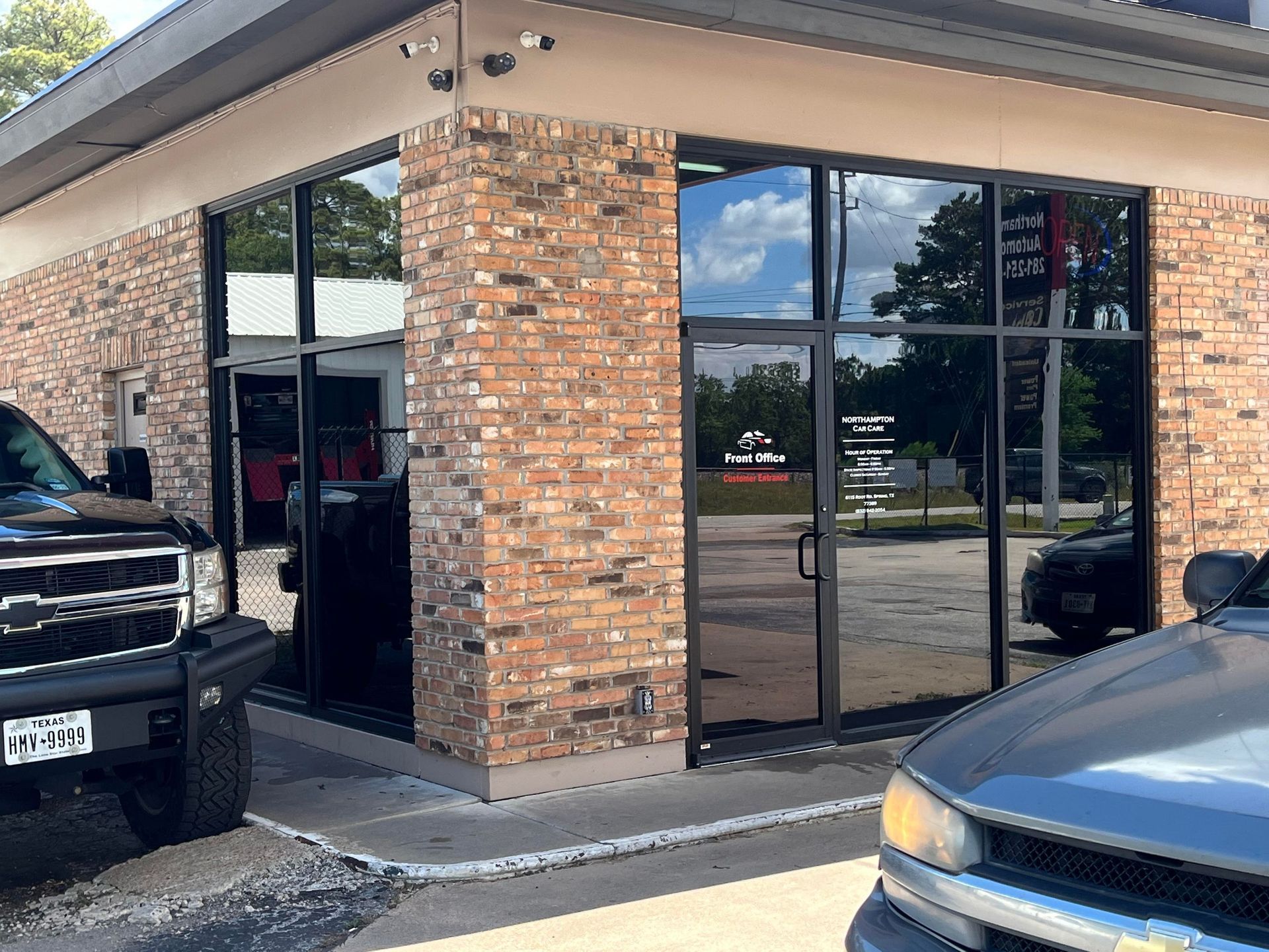 Building with brick exterior and dark tinted windows; parked cars in front.