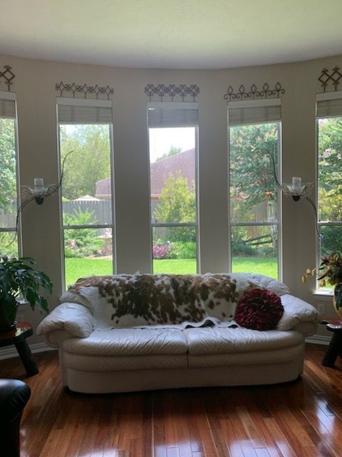 Living room with white sofa in front of large windows, cowhide throw, red pillow.
