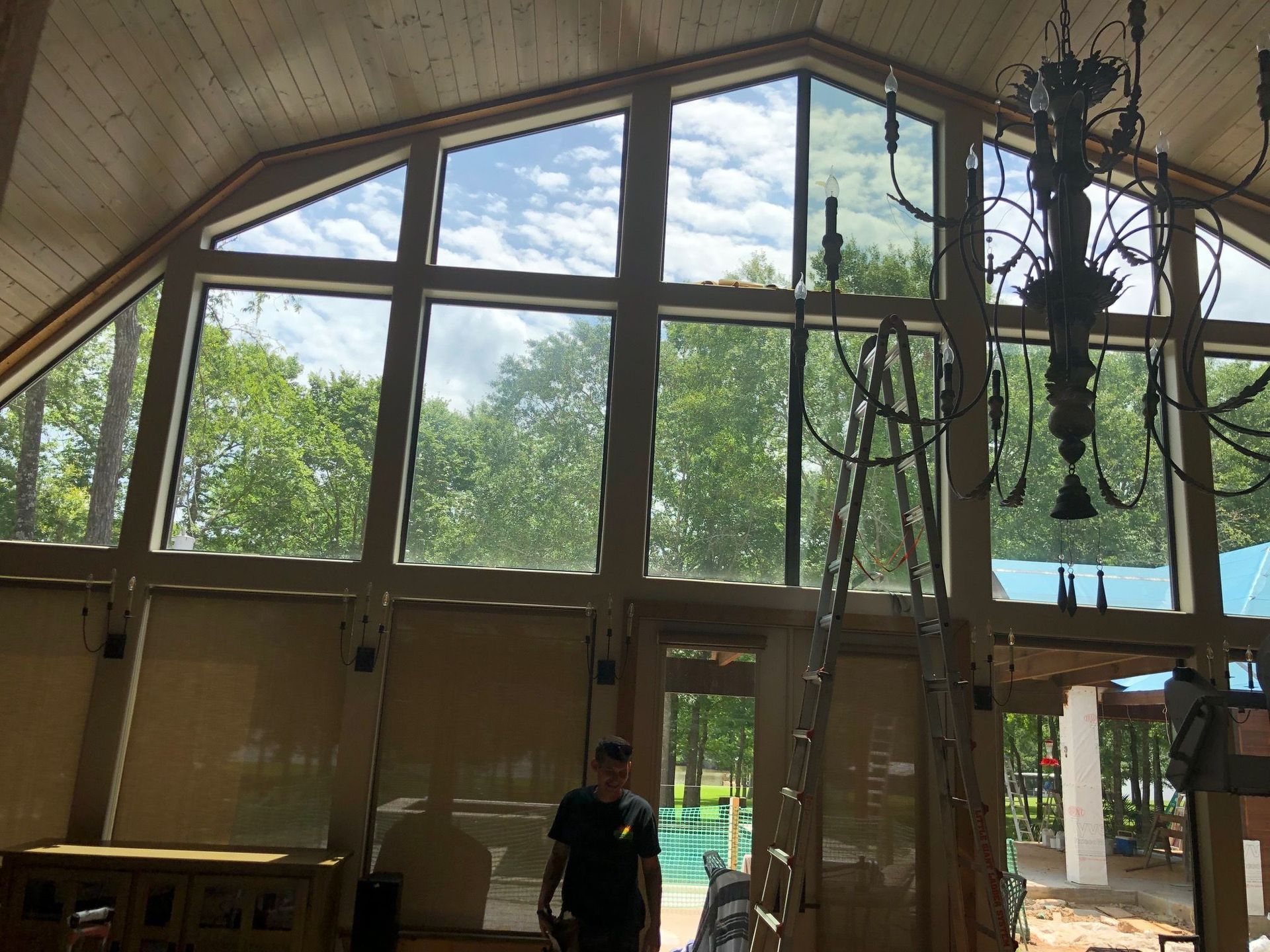 Large window, wooden ceiling, man inside, trees visible through the glass.