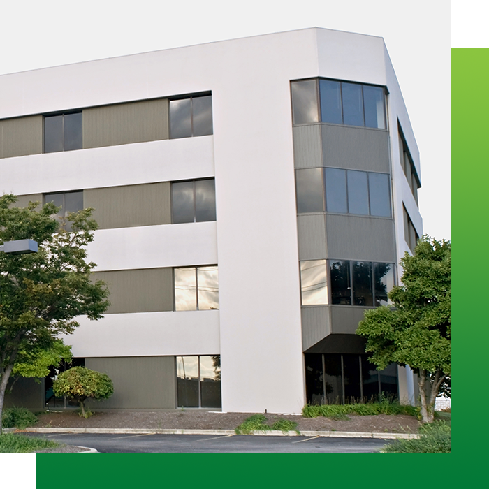 Office building exterior with white and gray facade, trees in front.
