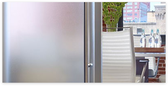Stainless steel refrigerator door next to outdoor table with water bottles and cityscape.