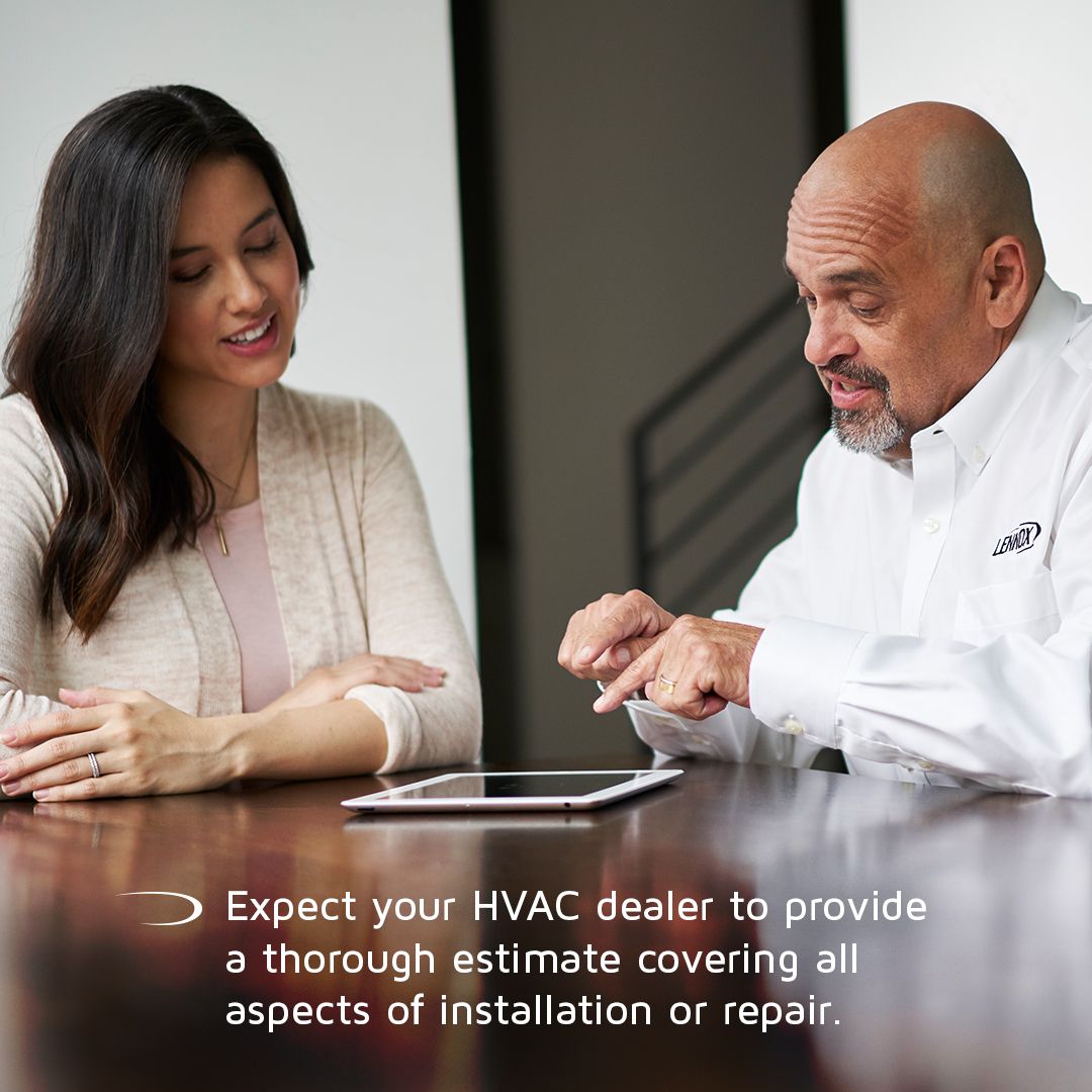 A man and a woman are sitting at a table looking at a tablet.