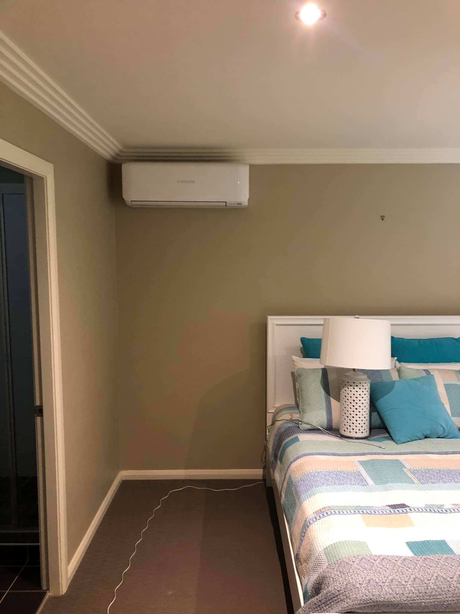 A Bedroom With a Bed, Lamp, and Air Conditioner — Steve's Air Conditioning in Shellharbour, NSW