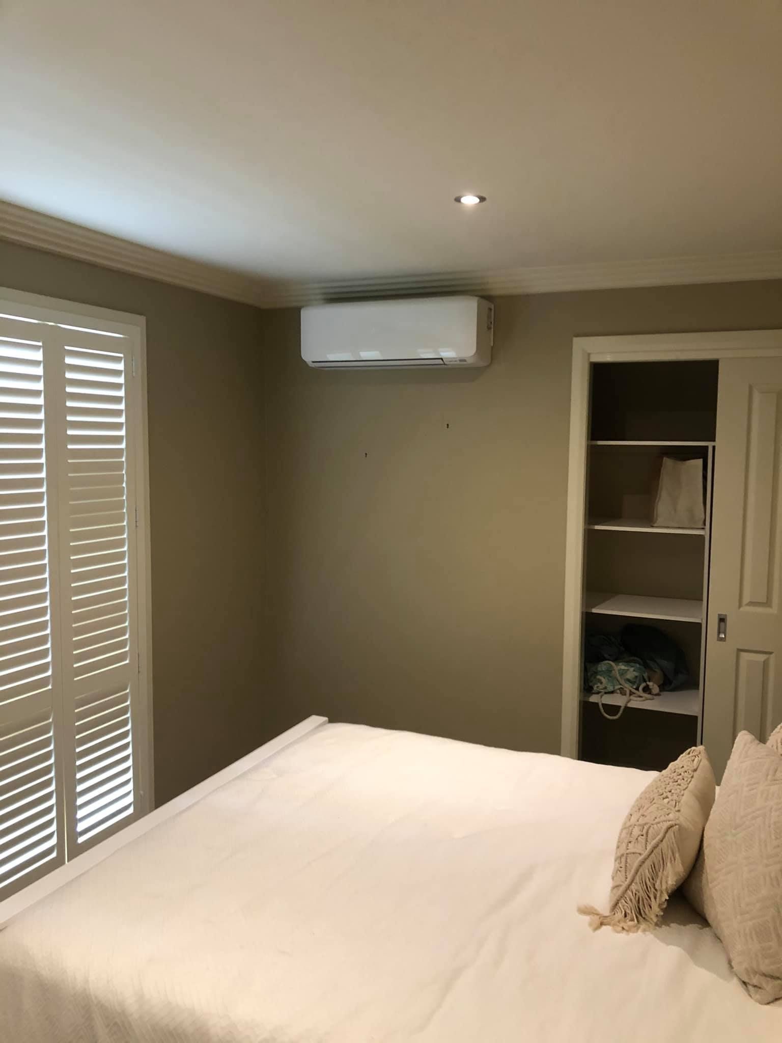 A Bedroom With a King Size Bed and a Window With Shutters — Steve's Air Conditioning in Lakeside Dr, NSW