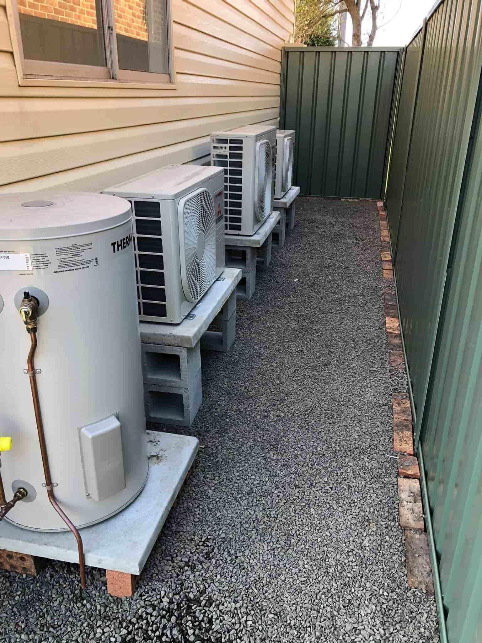 A Row of Water Heaters Are Sitting Next to Each Other in a Gravel Area — Steve's Air Conditioning in Lakeside Dr, NSW