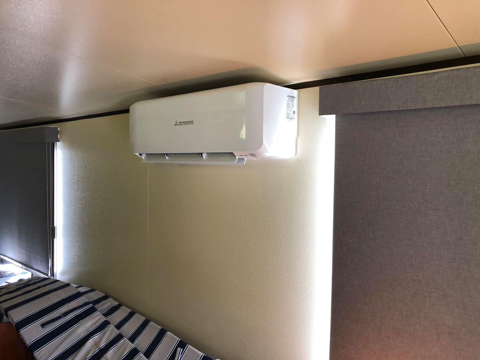 A Bedroom With a Bed and a Wall Mounted Air Conditioner — Steve's Air Conditioning in Lakeside Dr, NSW