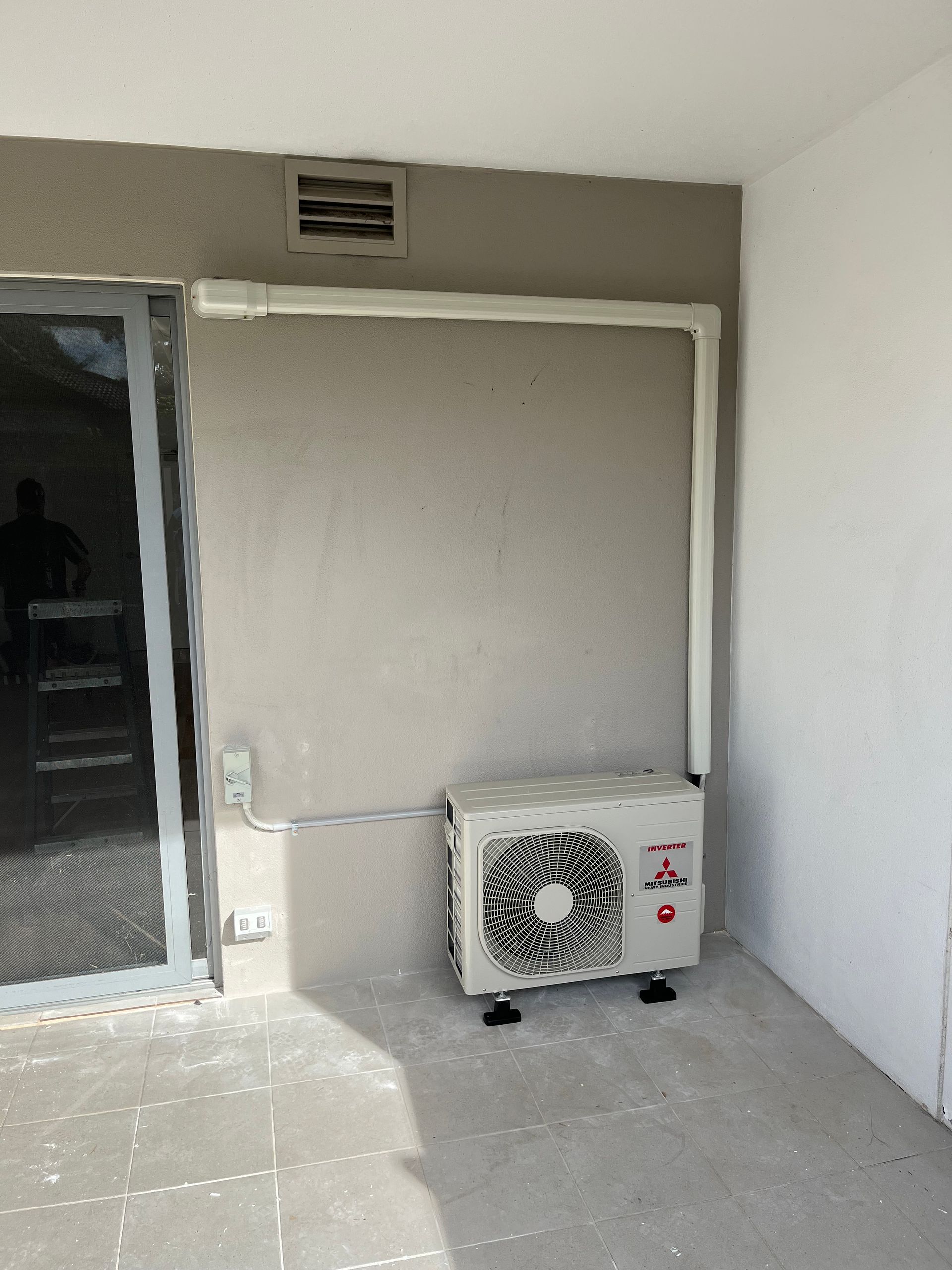 An lg air conditioner is sitting in a room next to a door.